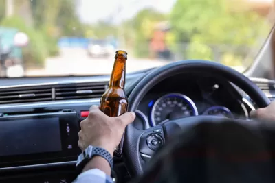 Man driving car and holding alcohol bottle