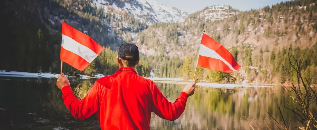 Man holding flags of Austria on border