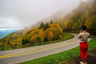 Man photographing nature in autumn on the road